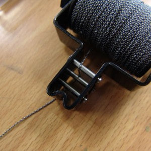 Close-up photo of Spigarelli string serving tool showing how the string is threaded.